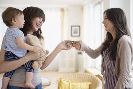 A Teen holding a baby and exchanging money with an adult.